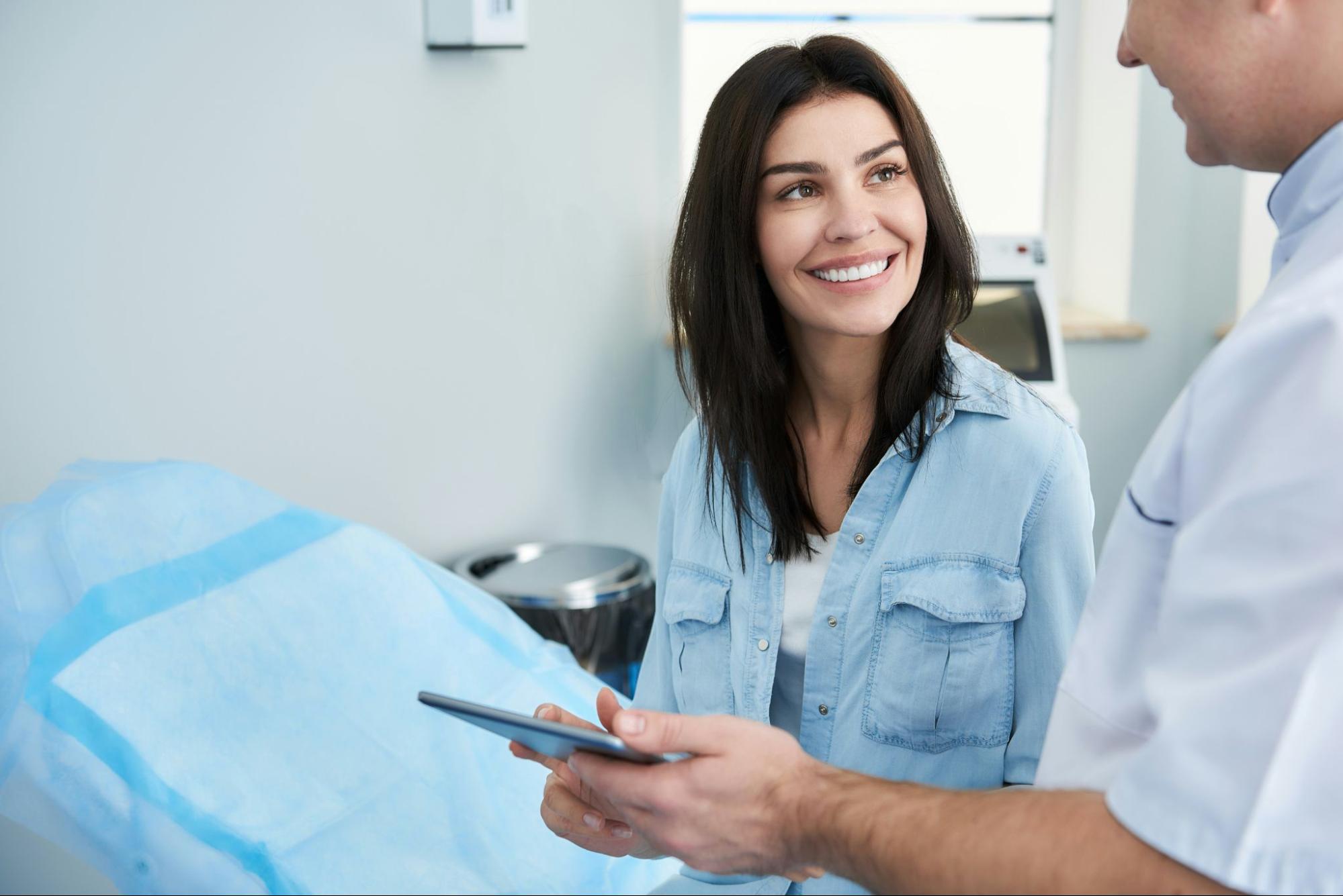 A patient smiling during a personalized consultation with a medical professional at The Collins Center in Connecticut to discuss a mommy makeover plan.